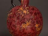 a red vase sitting on top of a wooden table