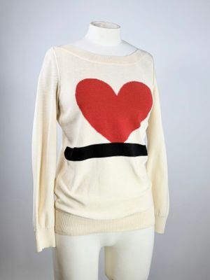 une photo d'un pull blanc orné d'un cœur rouge