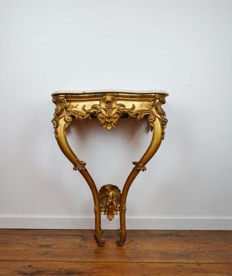 a gold console table with a marble top on a wooden floor