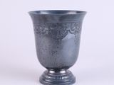 a silver vase that is sitting on a white surface