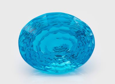 un objet en verre bleu posé sur une surface blanche