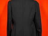 an image of a black suit on a mannequin stand against a red background