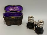 une paire de jumelles anciennes en métal argenté, avec un étui en velours violet