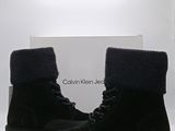 Les bottes sont noires et ornées de fourrure sur un fond blanc.