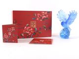 a blue bird sitting next to a red box and a blue vase