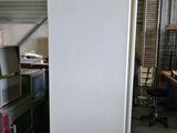a white refrigerator in a garage with other appliances in the background