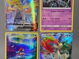 Quatre cartes Pokémon différentes sont représentées sur une surface grise.