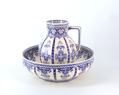 un bol et un pichet bleus et blancs posés sur une table blanche