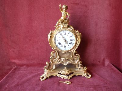 a gold clock with a bird on top of it
