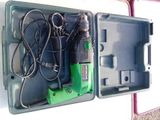une perceuse électrique verte et noire dans un étui en plastique