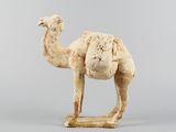 statue d'un chameau debout sur un socle en bois, sur fond gris