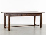 une table en bois avec un tiroir en dessous, posée sur un sol en béton