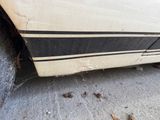 a white car with black stripes parked on the side of the road