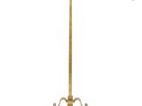 a tall brass floor lamp with a white shade on top