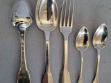 cinq cuillères en argent et deux cuillères en argent sur une table