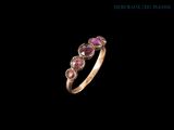 un gros plan d'une bague en or sertie de pierres roses sur fond noir