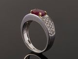a close up of a ring with a ruby stone and diamonds