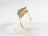 a close up of a gold ring with a ruby and diamond center