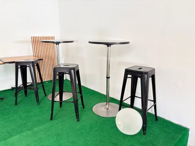 plusieurs tabourets et tables dans une pièce recouverte d'une moquette verte