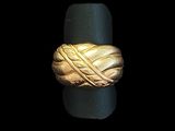 une image montrant un gros plan d'une bague en or posée sur une surface noire