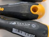three black and yellow screwdrivers sitting next to each other on a white surface