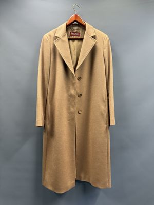 un manteau beige suspendu à un cintre devant un mur gris