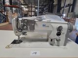 a white sewing machine sitting on a table in a warehouse