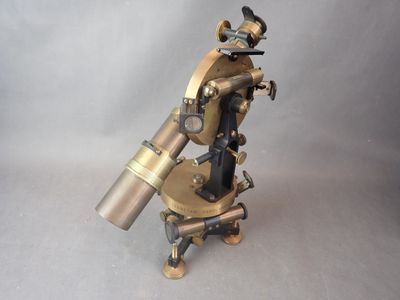une image représentant un microscope de couleur laiton posé sur un support, sur fond gris