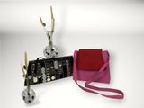 a pink purse with a red strap next to it and a silver vase with flowers