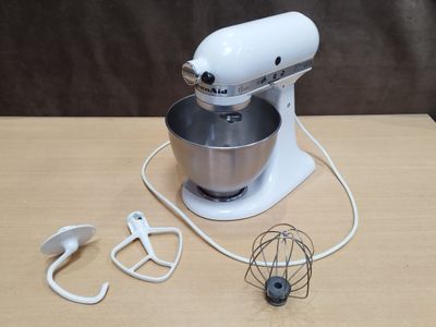 un batteur blanc posé sur une table, à côté d'un fouet en fil de fer