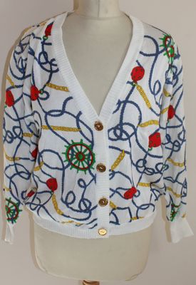 un gros plan sur le torse d'un mannequin portant un cardigan blanc orné de fleurs bleues et rouges