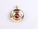 a close up of a gold pendant with a red stone
