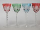 four different colored wine glasses sitting next to each other on a white surface