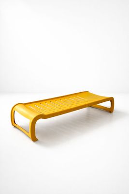 une image représentant un banc jaune posé sur un sol blanc