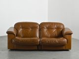 brown leather two seat sofa in corner of room with white wall