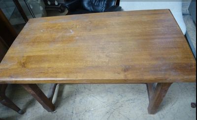 une petite table en bois avec une chaise noire en arrière-plan