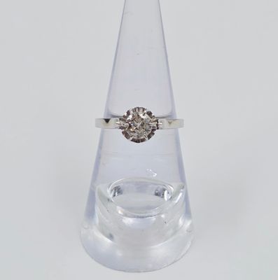 une bague en diamant posée sur un vase transparent