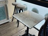 tables and stools in front of a window with a view of a street