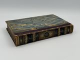 an old book sitting on top of a white table next to a white wall