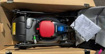 une boîte contenant une tondeuse à gazon rouge et noire