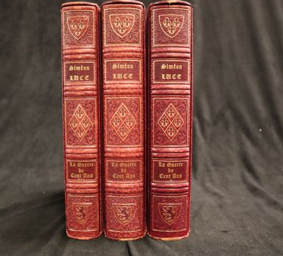 trois livres en cuir rouge posés sur une table recouverte d'un tissu noir