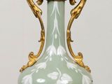 a green and gold vase sitting on a table