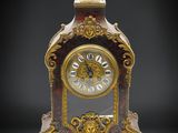 une horloge dorée et rouge posée sur une surface noire