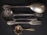 a lot of silver spoons and forks on a black table