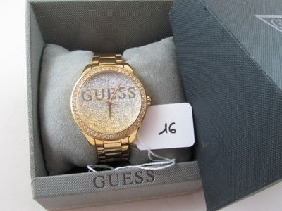 a gold watch in a box with a tag on it