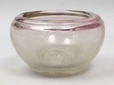 a glass bowl with a silver rim on a white surface