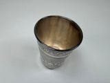 an old silver cup with a handle on a white surface