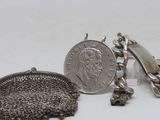 two pieces of silver jewelry sitting on top of a white surface