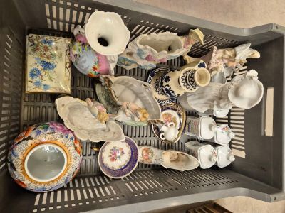 un panier rempli de tasses à thé et de soucoupes posé par terre