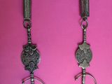 two silver necklaces on a pink background with a chain around them